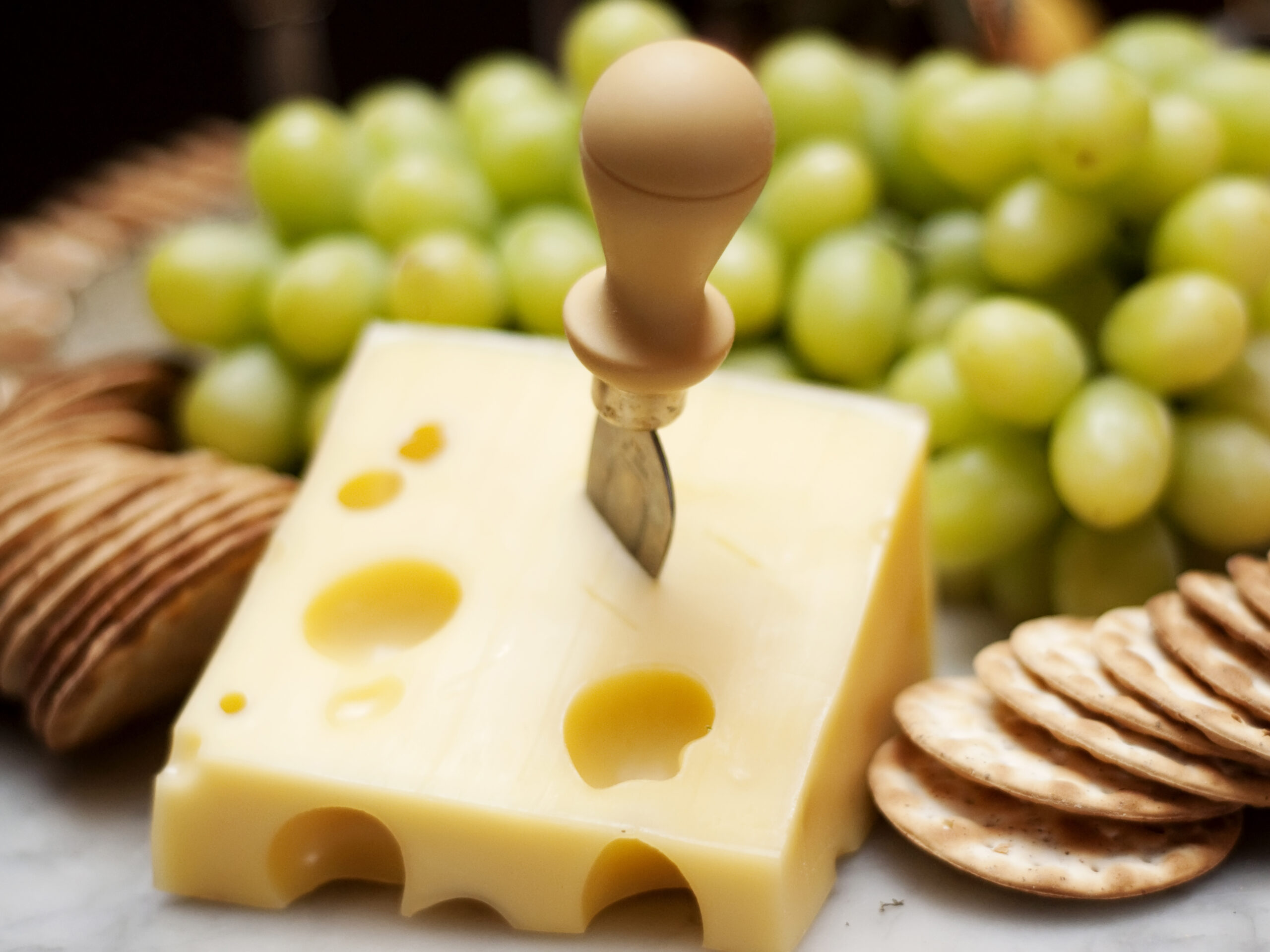 Cheese, crackers and green grapes spread on platter.