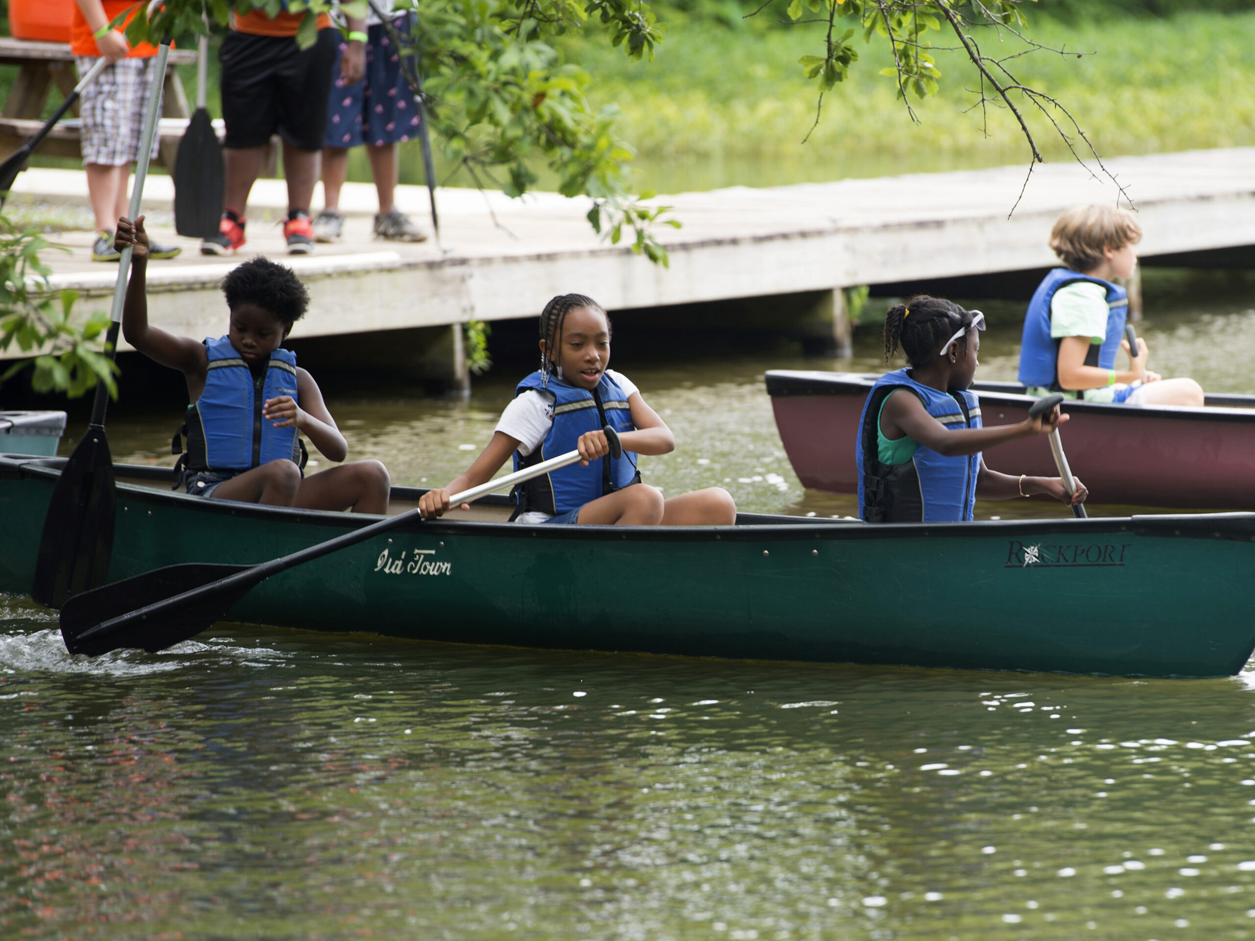 kids in canoes paddling away from the dock