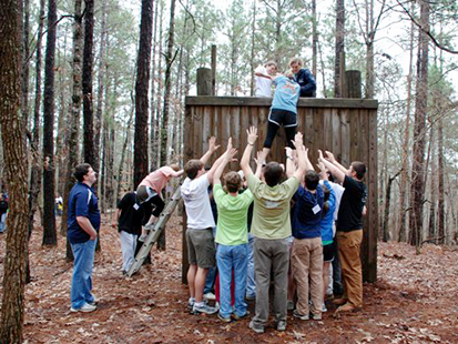 assisting a group member over the low ropes wall
