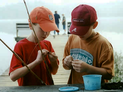 boys putting worms on the hooks of their fishing poles